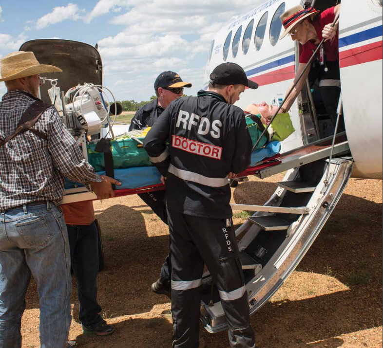 RFDS - An injured person in a stretcher being loaded onto an airplane by a Royal Flying Doctor and other people.